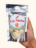 Ajo entero pelado fresco Los Nietos, envase de 120 g sostenido en una mano sobre fondo crema.