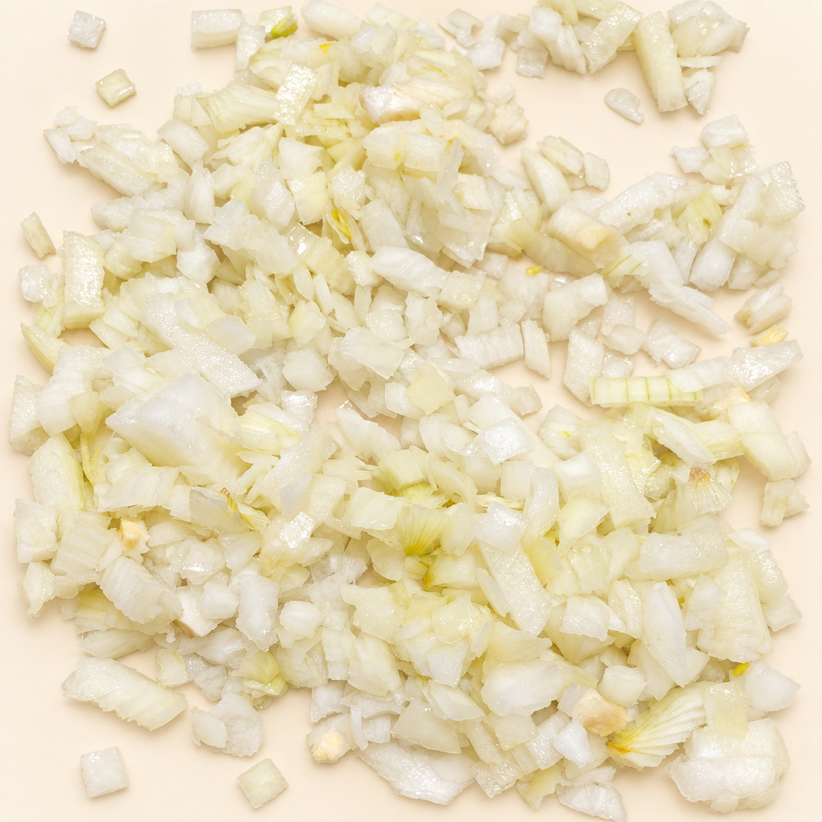 Detalle de cebolla blanca fresca picada en cubitos sobre fondo crema.