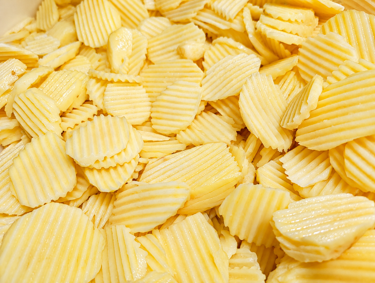 Detalle de papas frescas cortadas en rodajas acanaladas, listas para cocinar.