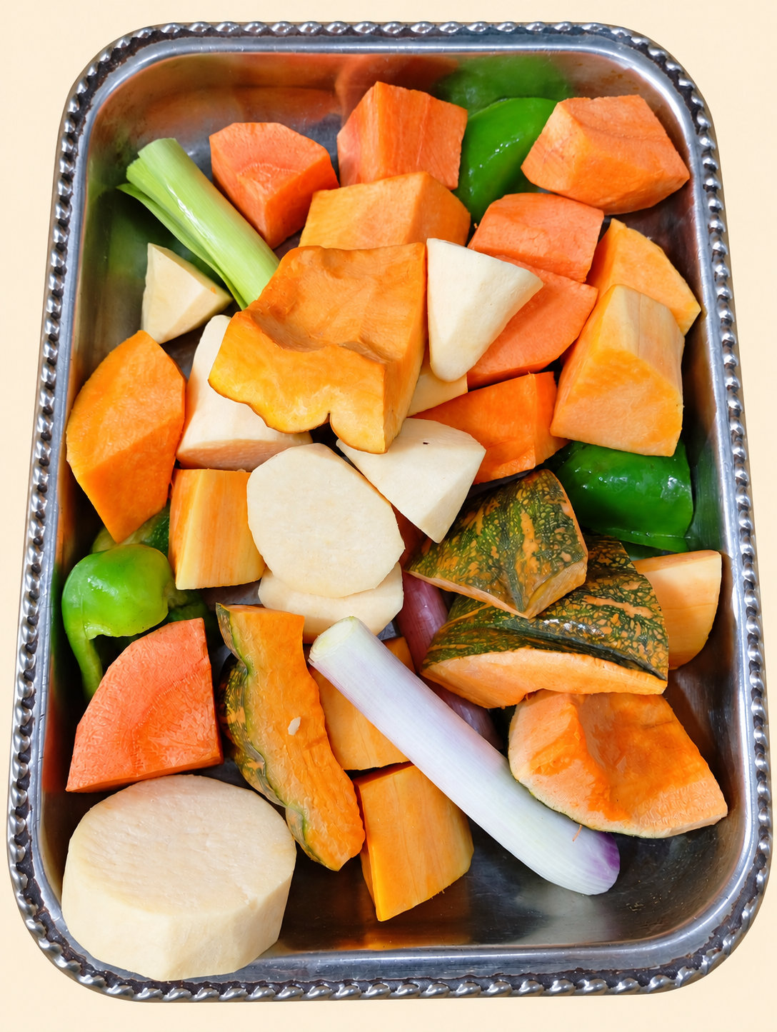 Vegetales frescos para horno Los Nietos, cortados en trozos y presentados en una bandeja metálica sobre fondo crema.