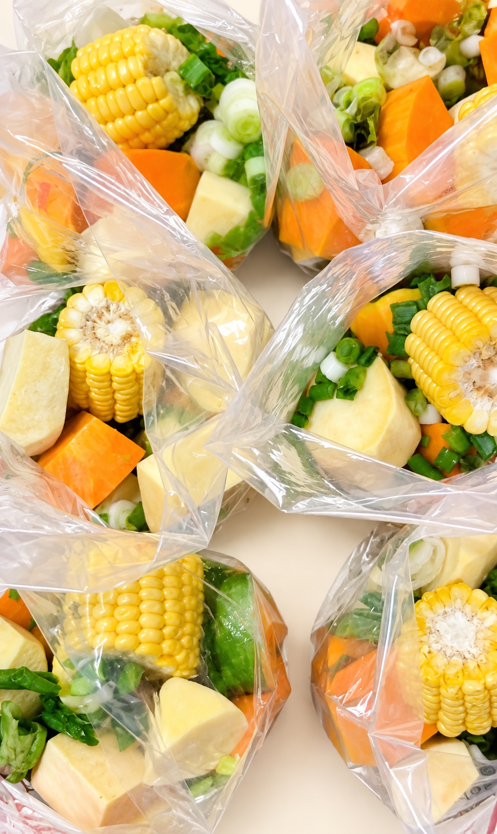 Bolsas de vegetales para sopa con choclo, calabaza y verduras visibles sobre fondo crema.