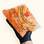 Zanahoria fresca en cubitos Los Nietos, envase de 750 g sostenido con guante sobre fondo crema.