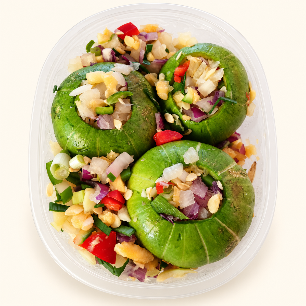 Tres zapallitos ahuecados con mezcla de verduras frescas para cocinar, en su bandeja transparente.